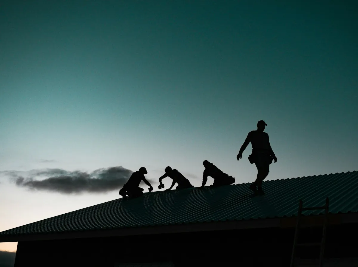 Roof Replacement in East Orange — a roofing crew silhouetted on a roof at dusk