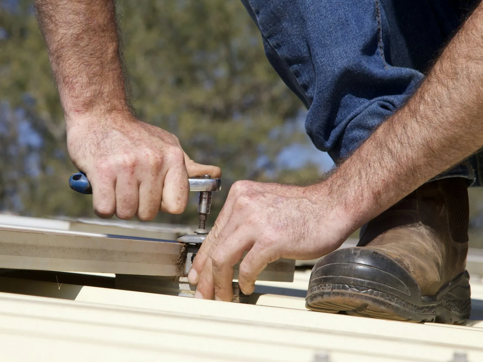 Roof Replacement in East Orange — a roofer's hands tightening a fastener with a ratchet